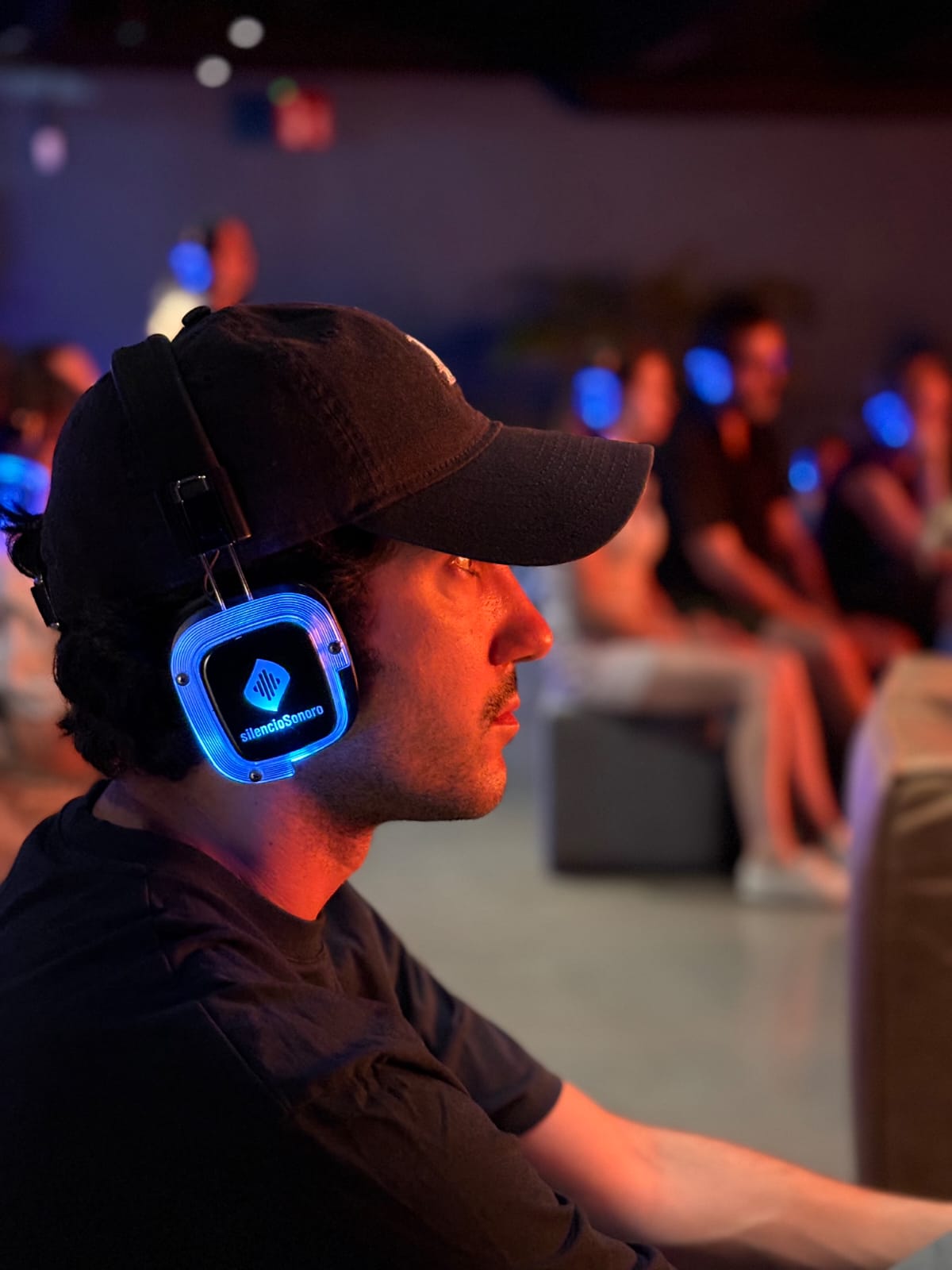 Publico escuchando con auriculares inalambricos, luces de fondo desenfocadas