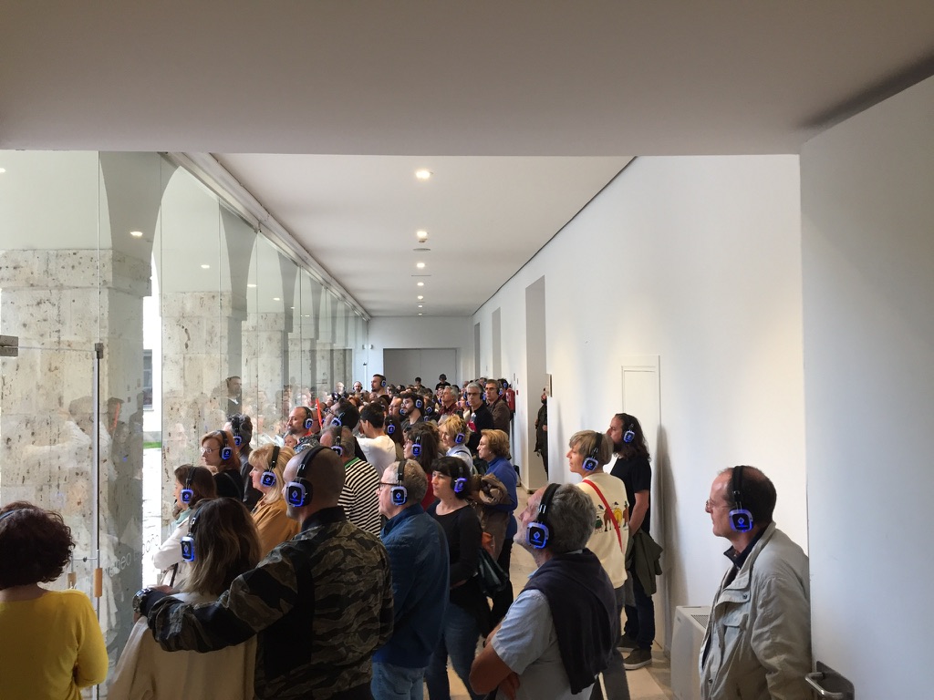 Publico con auriculares inalambricos siguiendo el recorrido por la galeria del museo