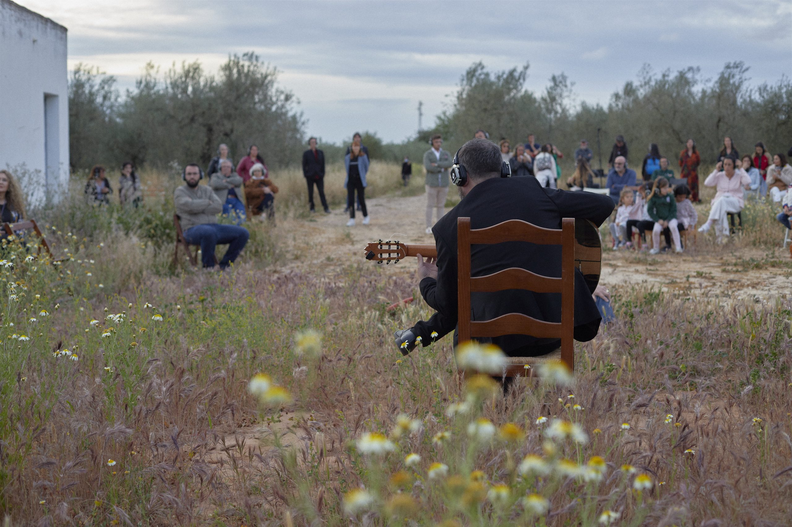 Publico con auriculares inalambricos escuchando el recital de Eduardo Trassierra en el olivar de La Aceitera