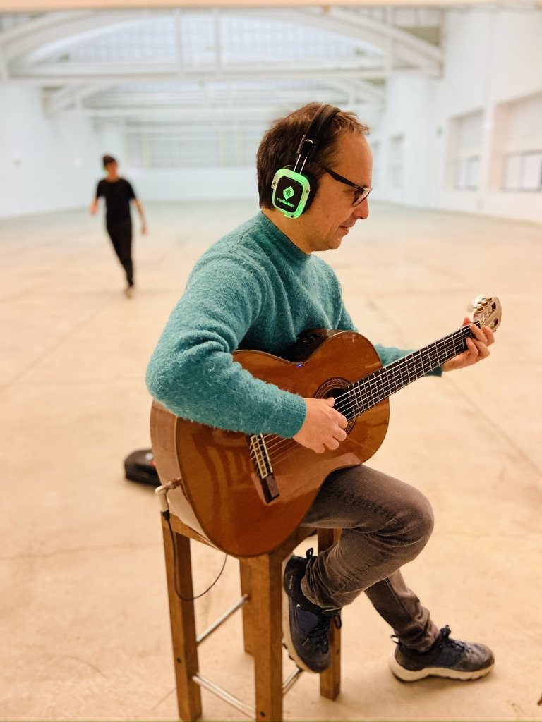 Guitarra en directo escuchada por auriculares inalámbricos por el público de Al Otro Lado