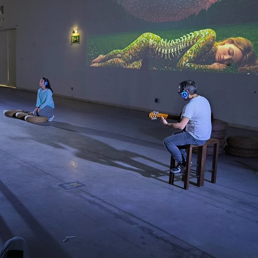 Proyección de imagen generativa sobre el muro durante Al Otro Lado, con guitarra en directo