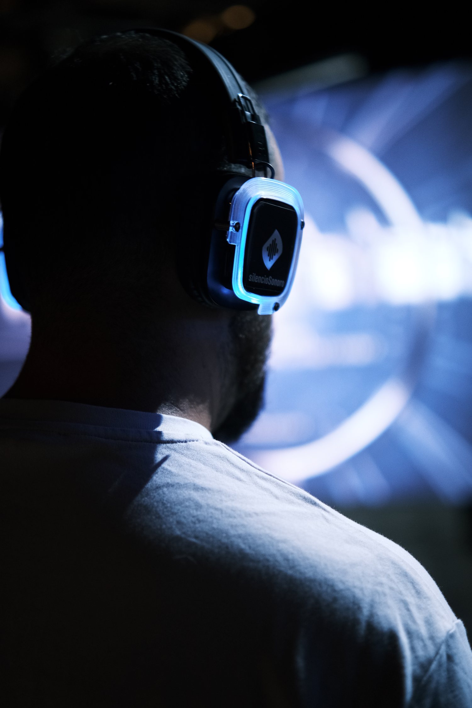 Auriculares inalámbricos iluminados en azul durante la escucha de Madrid Concrete